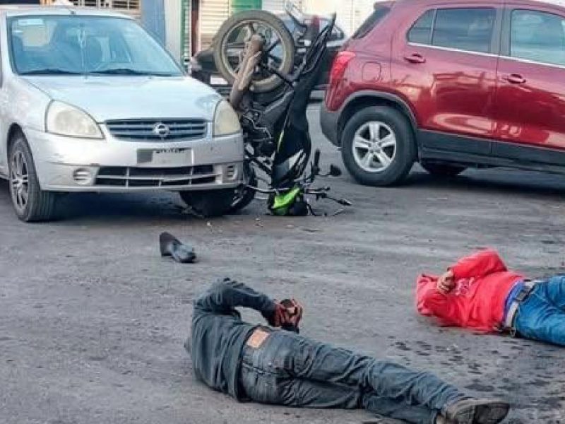 Impactan motociclistas en  auto y salen disparados; hay dos lesionados